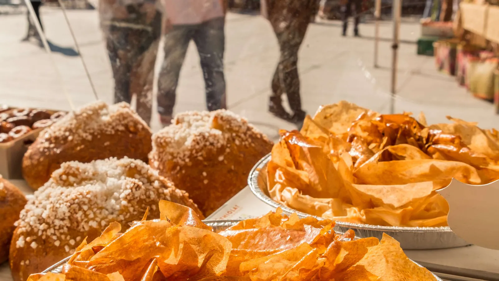 Display of fresh bread and pastries at Pey Berland market in Bordeaux, featuring sugar-dusted brioche and golden croissants on serving trays.