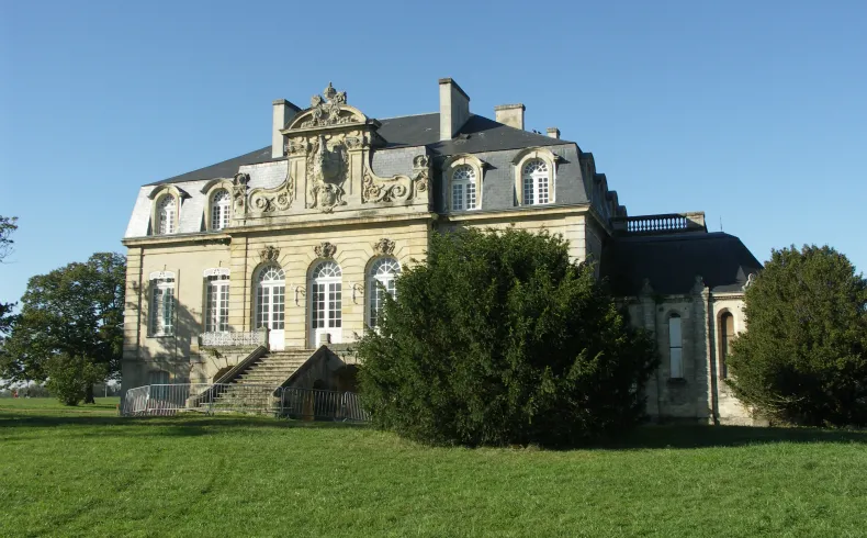 A Second Empire manor house at Beauval Estate in Bordeaux, featuring stone façade, mansard roof, and ornate architectural details, surrounded by green grounds.