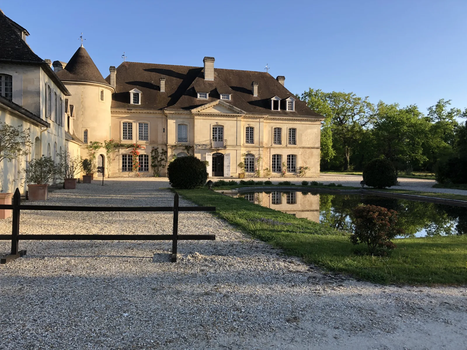 Château Bouscaut in Bordeaux, an elegant wine estate featuring a stone facade, mansard roofs, and classical architectural details, surrounded by a reflecting pond and manicured grounds.