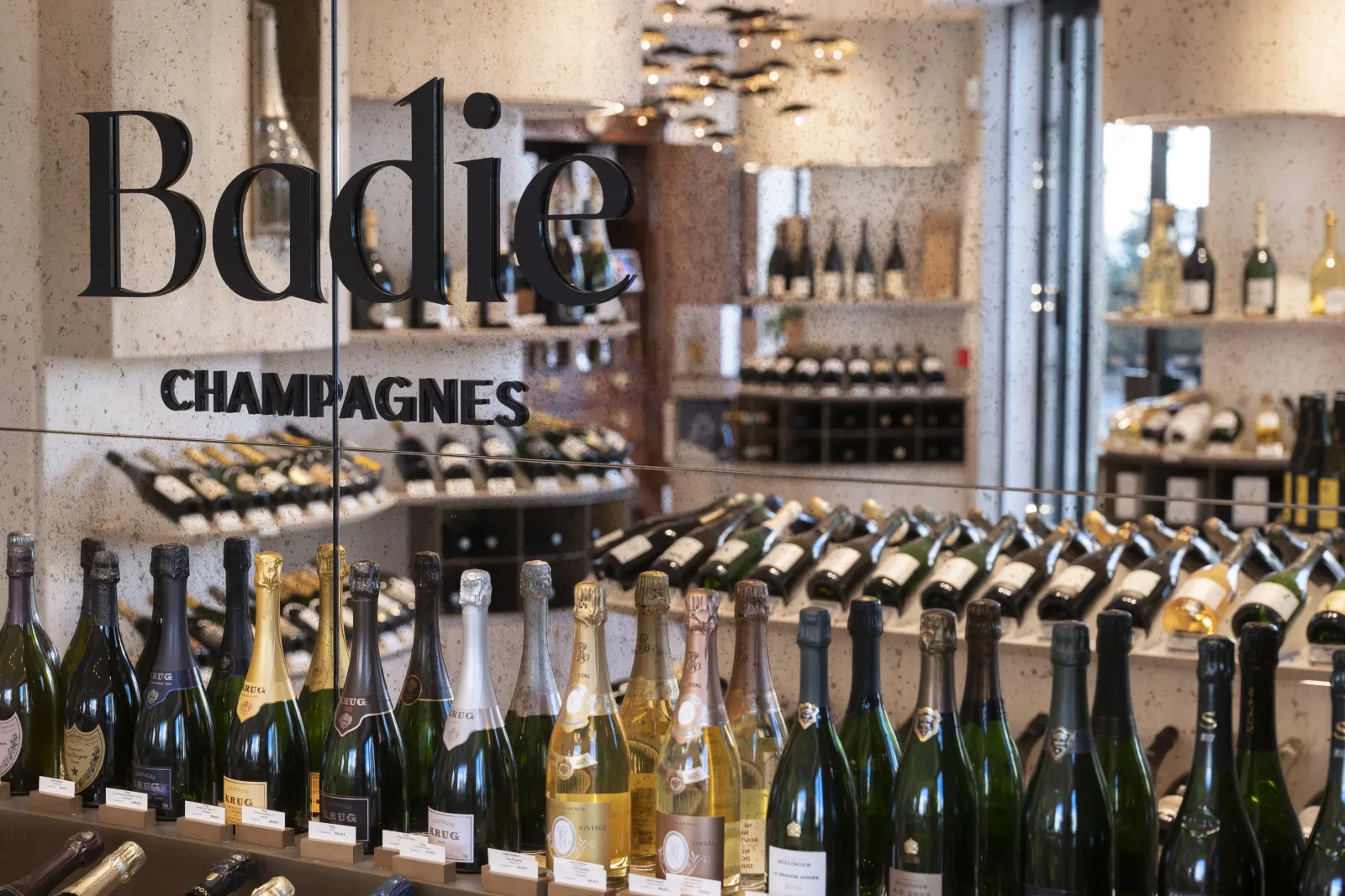 Storefront of Badie Champagnes shop in Bordeaux displaying rows of champagne bottles in the window and filled shelves in the background