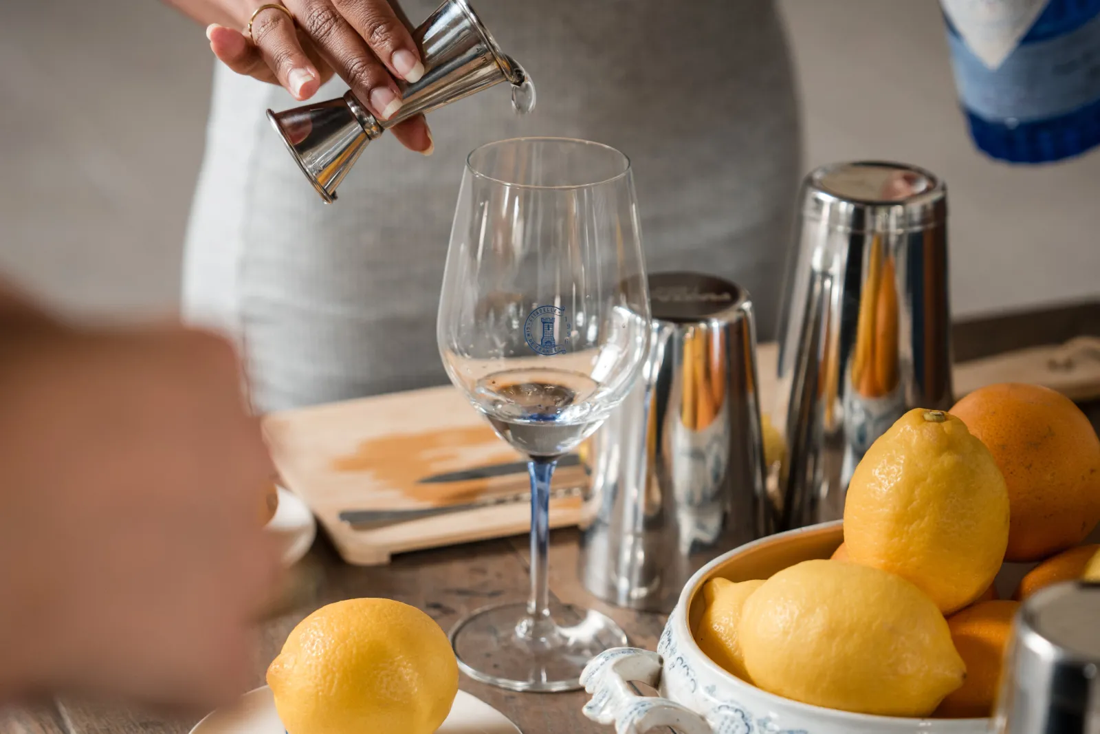 Gin tasting at Citadelle Distillery in Bordeaux: a hand pours gin into a wine glass surrounded by fresh lemons and gin bottles.