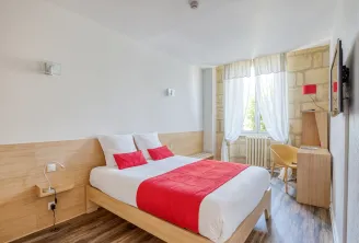 Modern hotel room with a light wooden double bed, white bedding and red blanket, at the Hotel des Voyageurs in Bordeaux