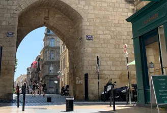 View of Rue de Cheverus in Bordeaux passing under a stone arch, with the Cassonade café visible on the right and Haussmann-style buildings in the background.