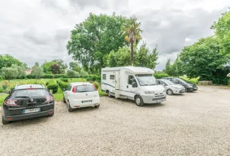 Motorhomes and cars parked at Château Beau Rivage in Bordeaux, surrounded by green trees under a cloudy sky