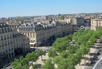Aerial view of Allées de Tourny in Bordeaux featuring Haussmann-style buildings, green trees, and stone facades.