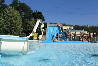 Water park at Pessac Nautical Stadium in Bordeaux featuring a blue water slide, swimming pool, and visitors enjoying a sunny day.