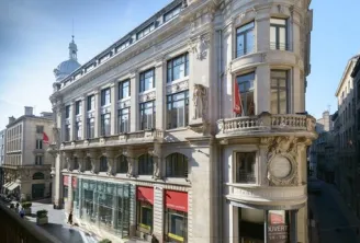 Ornate facade of the Galeries Lafayette building in Bordeaux, Beaux-Arts architecture with balconies and balustrades, French flags visible