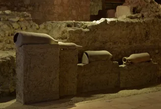 Archaeological remains from the Saint-Seurin site in Bordeaux: ancient pottery and ceramic fragments displayed on stone blocks in an underground excavation.
