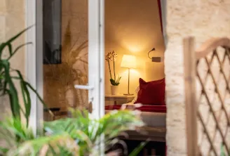 View through an open door of an elegant hotel room with warm lighting, table lamp, green plant and red cushion, Hotel Churchill in Bordeaux