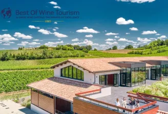 Maison Cardinale in Bordeaux, a modern building with panoramic terrace overlooking Bordeaux vineyards under clear blue sky. Best of Wine Tourism 2023 logo visible.