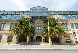 Front façade of Mercure Bordeaux Château Chartrons hotel in Bordeaux, featuring a historic stone building with modern glass roof structure and two palm trees