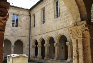 Inner courtyard of the Convent of the Annunciation in Bordeaux featuring Romanesque arcade gallery with carved columns and stone buildings