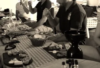 Group of people gathered around a table with dishes and glasses during a convivial meal in black and white