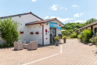 Kyriad Direct Bordeaux South Cestas hotel entrance with reception area, lounge seating, and landscaped grounds under clear skies