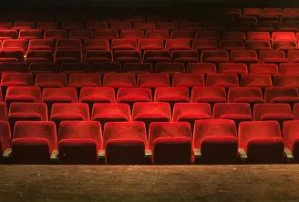 Empty red theater seats arranged in rows inside the Molière Theater in Bordeaux, illuminated and tiered.