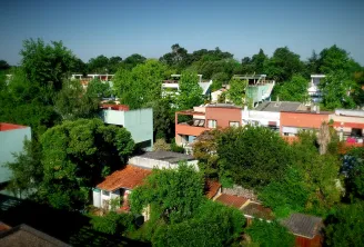 Aerial view of the Cité Frugès in Pessac, a modern residential district designed by Le Corbusier featuring white, red, and green houses surrounded by lush greenery.