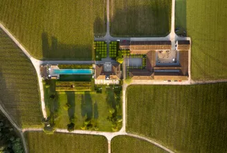 Aerial view of Château du Tertre near Bordeaux showing stone buildings, a blue swimming pool, manicured gardens and surrounding vineyards