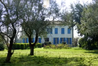 Beau Rivage Estate near Bordeaux, white stone mansion with blue shutters surrounded by olive trees and manicured gardens