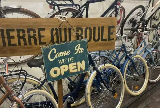 Pierre qui Roule bike rental shop in Bordeaux displaying multiple blue and brown bicycles with an "Come In WE'RE OPEN" sign