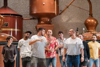Group of visitors walking through the Citadelle Gin distillery in Bordeaux, with traditional copper stills in the background.
