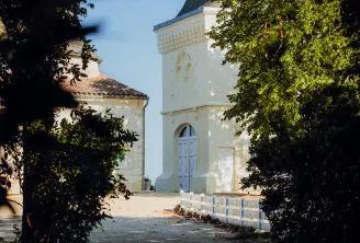 White church with pointed black steeple surrounded by lush green foliage in Bordeaux