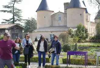 Guided tour at Bordeaux's Market Garden Museum with visitors walking through vegetable gardens in front of a castle with conical towers.