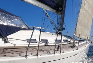 White sailing yacht with sails raised against clear blue sky, showing deck details and rigging, moored at Bordeaux with Arguin Sailing branding.