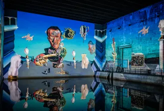 Immersive installation at Bordeaux's Bassins des Lumières featuring a surreal projection with sculptures and fantastical elements reflected in water, creating a dreamlike atmosphere in shades of blue and gold.