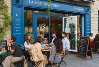 Blue storefront of La Manufacture Le Bayon in Bordeaux with customers seated at outdoor tables in front of the café-restaurant