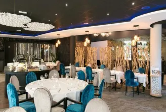 Elegant restaurant interior with round dining tables, blue and grey chairs, natural wood decoration, dark blue ceiling and modern lighting fixtures