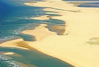 Aerial view of Arcachon Basin featuring golden sandbars, turquoise waters, and winding channels along the Atlantic coast