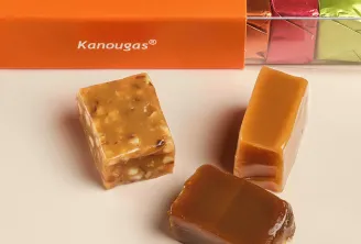 Three Kanougas from Pariès house, Basque delicacies from Bordeaux, displayed in front of an orange box with logo since 1895