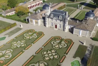 Aerial view of Château de Malle in Bordeaux featuring ornamental parterre gardens with spiral and scroll designs, domed towers, and formal French gardens