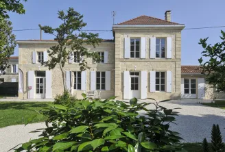 Front facade of Château d'Osmond in Bordeaux, stone building with white shutters, main entrance, and landscaped garden