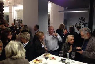 Guests in business attire networking at a wine tasting event at Max Bordeaux Wine Gallery & Cellar, with charcuterie plates and wine glasses on tables.