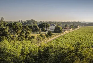 Aerial view of Château Giscours near Bordeaux, featuring its white neoclassical manor house surrounded by lush vineyards and forests in the Médoc region.