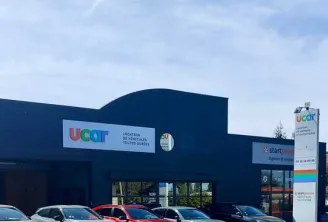 UCAR car dealership in Bordeaux displaying multiple used vehicles in front of the showroom under a partly cloudy sky