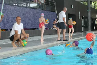 Water polo training session at Bordeaux's Tissot municipal swimming pool with children in the water and a coach on the pool deck