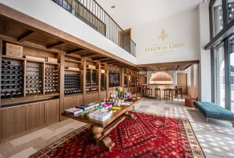 Elegant interior of Château Fleur de Lisse in Bordeaux, featuring wooden wine storage racks filled with bottles, a tasting counter, and refined interior design with white walls and exposed beams.