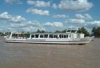 The cruise boat Aquitania sails on the Garonne river in Bordeaux, a white river tourism vessel with passengers visible on board.