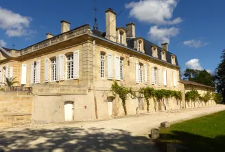 Château Sainte Barbe in Bordeaux, a classical stone manor house with mansard roof, white shuttered windows, and surrounding green grounds.