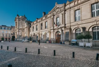 Paved square in Bordeaux featuring Notre-Dame Church and historic stone buildings under clear blue sky