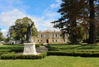 Château Marquis de Vauban in Bordeaux featuring an ochre stone façade surrounded by formal gardens, towering trees, and a contemporary sculpture in the foreground