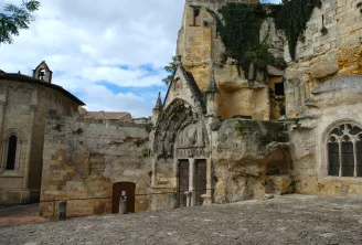 Ruins of a medieval stone church with Gothic portal, stained glass windows and ivy in the underground village of Saint-Émilion