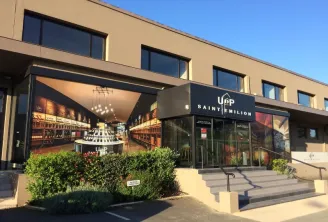 Modern storefront of Union of Saint-Emilion Producers in Bordeaux, featuring a wine bottle display window, stepped entrance and decorative plants