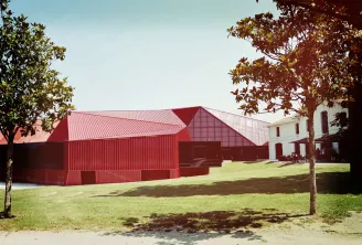 Rocher de Palmer in Cenon featuring modern red metal-roofed buildings and a historic white stone building set in a green landscaped park.