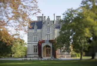 Château Lanessan in Bordeaux, a grand stone mansion with turrets and slate roof, surrounded by autumn foliage and red ivy.