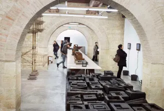 Vaulted underground gallery at Arc en rêve in Bordeaux featuring a modern architecture exhibition with black scale models on the floor, white display panels on walls, and visitors exploring the installations.