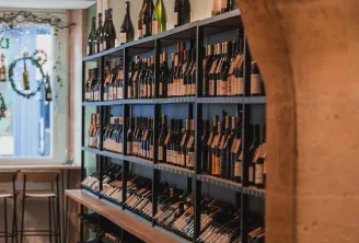 Wine display in ComplanTerra wine shop in Bordeaux, featuring bottles arranged on multiple black shelves with additional bottles displayed on top.