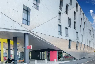 Modern white facade of Appart City Confort Bordeaux Chartrons with contemporary architecture, covered entrance with gray columns, pink signage and retail access in Bordeaux